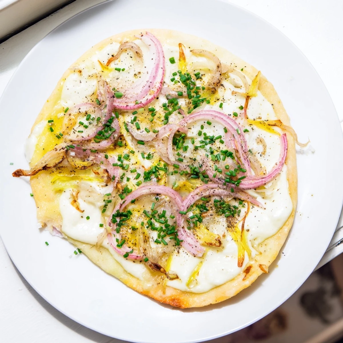 Crispy Savory Maultaschen Flatbread, topped with melted cheese, fresh herbs, and caramelized onions, ready to serve.