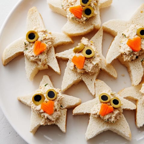 Bright, ocean-themed Mini Starfish Sandwiches with tuna filling, ready to serve on a white platter.
