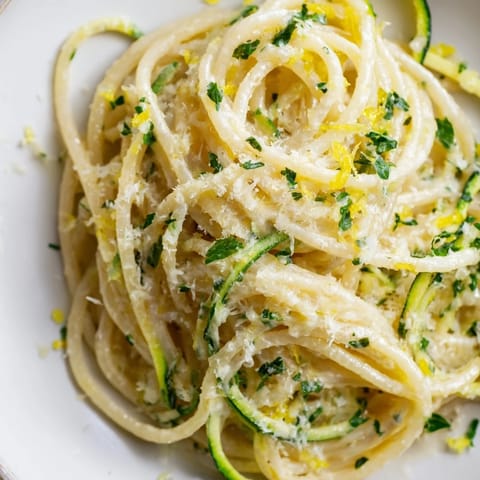 Leichtes Sommergericht aus spiralen Zucchini mit saftiger Zitronen-Knoblauch-Butter-Sauce und Parmesan über den italienischen Nudeln gerieben.