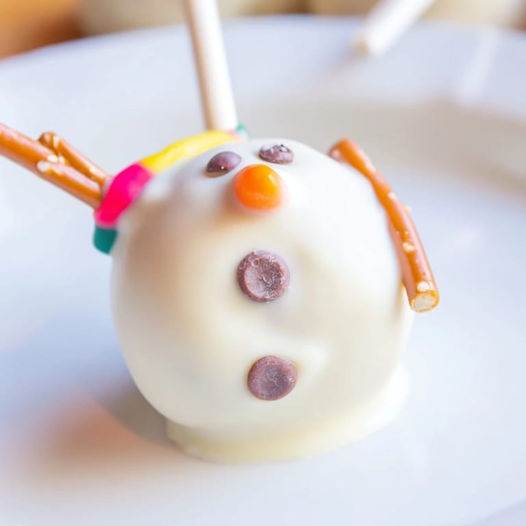 Delicious Oreo Snowman Cake Pops: adorable snowmen, decorated with chocolate chips, ready to eat.