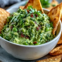Ein farbenfroher Dip aus cremiger Avocado und zarter Edamame, serviert mit knusprig gebackenen Vollkorn-Pitas.